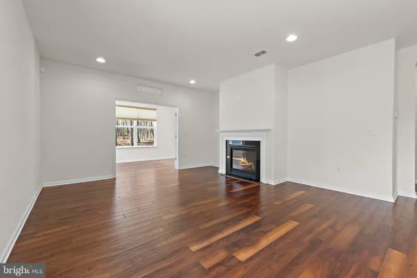 a view of a kitchen and an empty room with wooden floor