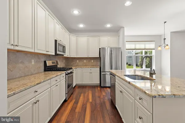 a kitchen with stainless steel appliances granite countertop wooden floors and white cabinets