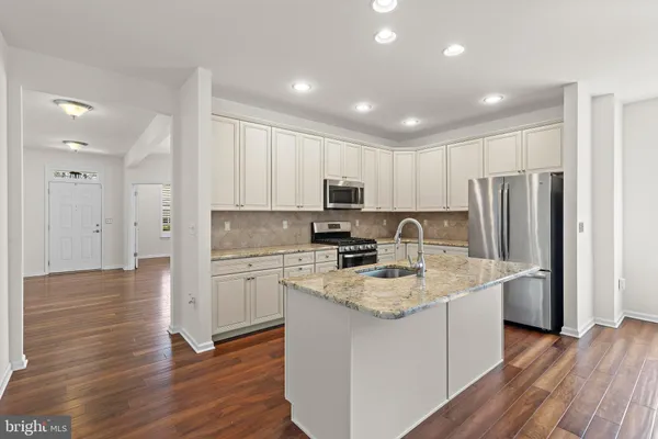 a kitchen with stainless steel appliances granite countertop a sink refrigerator and cabinets