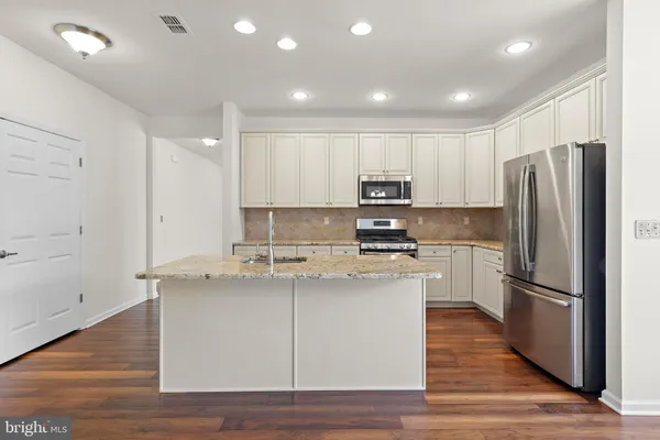 a kitchen with a refrigerator stove a sink and white cabinets with wooden floor