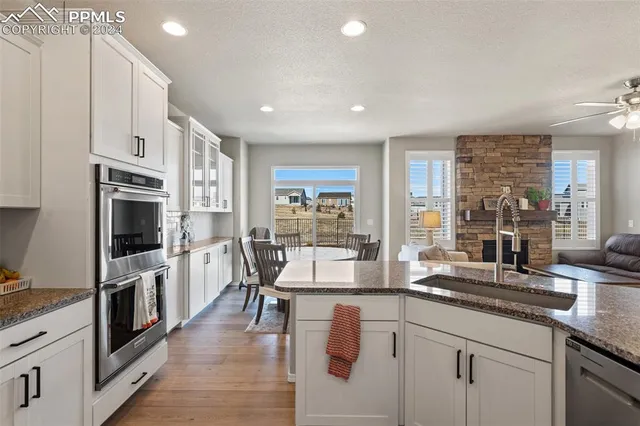 a kitchen with stainless steel appliances granite countertop a stove top oven a sink a dining table and chairs