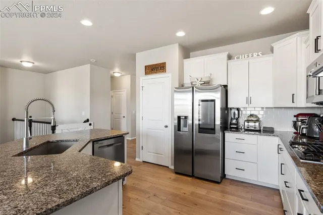 a kitchen with stainless steel appliances granite countertop a sink a stove and refrigerator