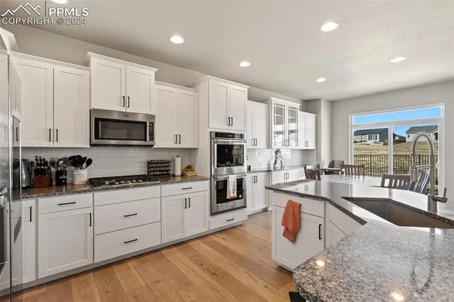 a kitchen with stainless steel appliances granite countertop a stove top oven a sink a dining table and chairs