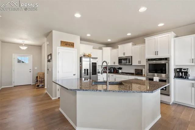 a view of a kitchen with kitchen island a counter top space a sink a refrigerator and a stove