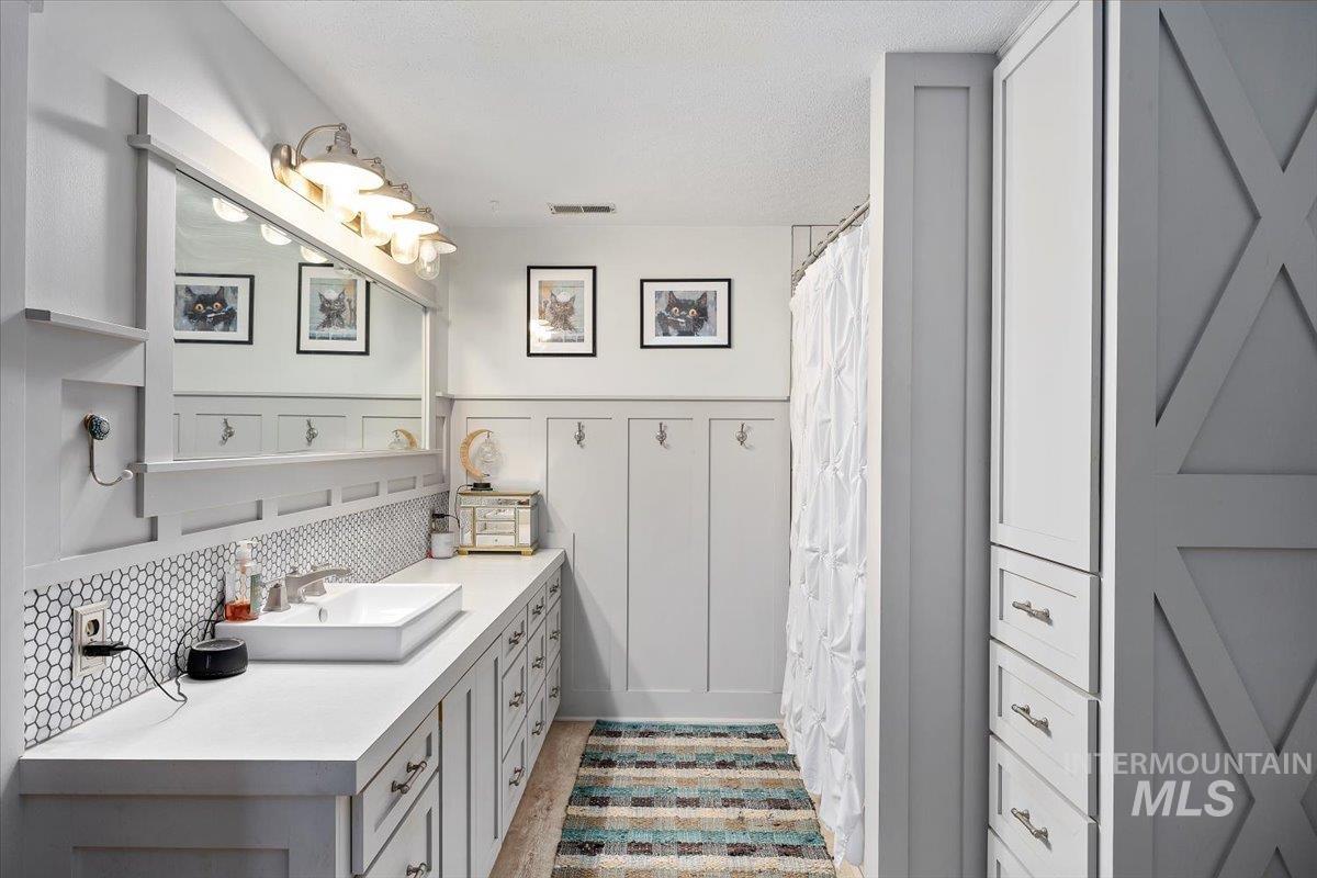 173 Main Line Ranch Road Rupert, ID 83350 - Photo 29 of 47 Bathroom with vanity, curtained shower, a wainscoted wall, and backsplash