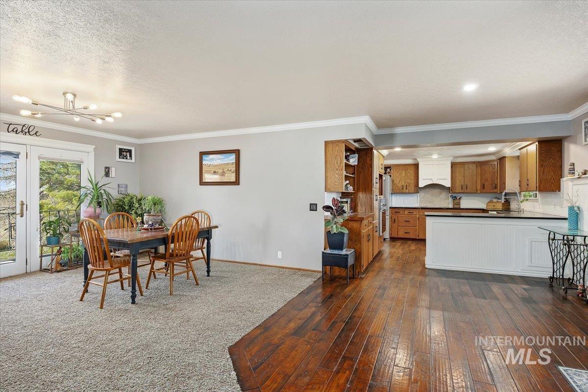 173 Main Line Ranch Road Rupert, ID 83350 - Photo 7 of 47 Dining area featuring crown molding, dark wood-type flooring, a chandelier, french doors, and a textured ceiling