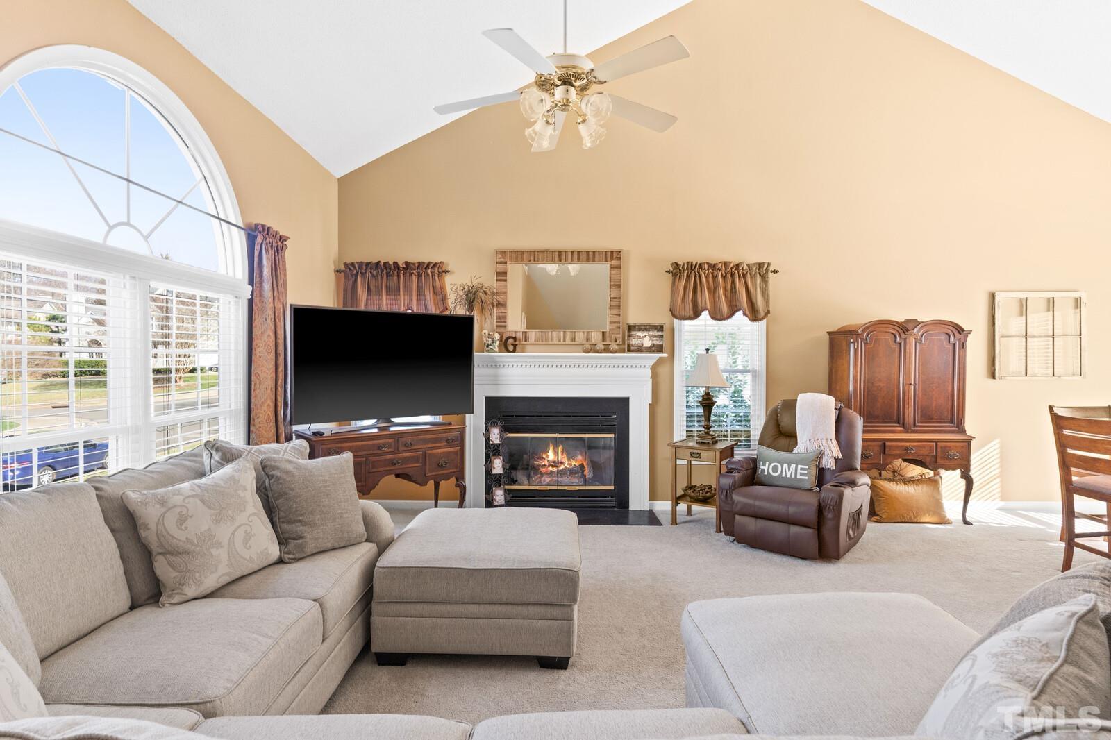 12104 Amoretto Way Raleigh, NC 27613 - Photo 5 of 21 a living room with furniture a fireplace and a flat screen tv