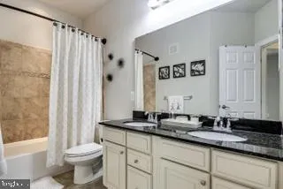 a bathroom with a granite countertop sink a toilet and a bathtub
