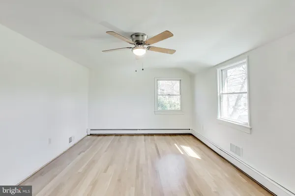 an empty room with wooden floor fan and windows