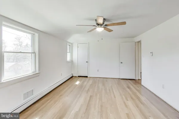 a view of empty room with wooden floor and fan