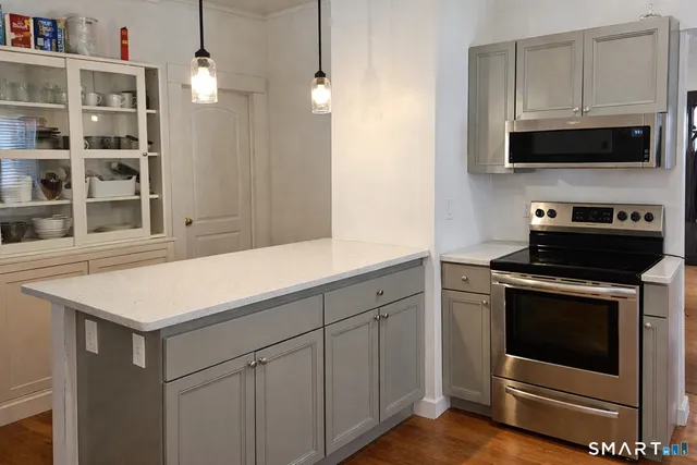 a kitchen with stainless steel appliances a stove a microwave and white cabinets