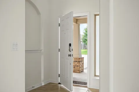 an empty room with wooden floor cabinet and windows