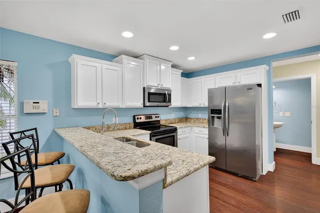 a dining room with wooden floor a chandelier a glass table and chairs