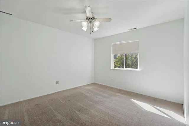 an empty room with a chandelier fan and windows
