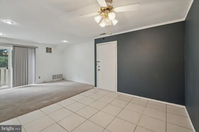a view of an empty room and chandelier fan