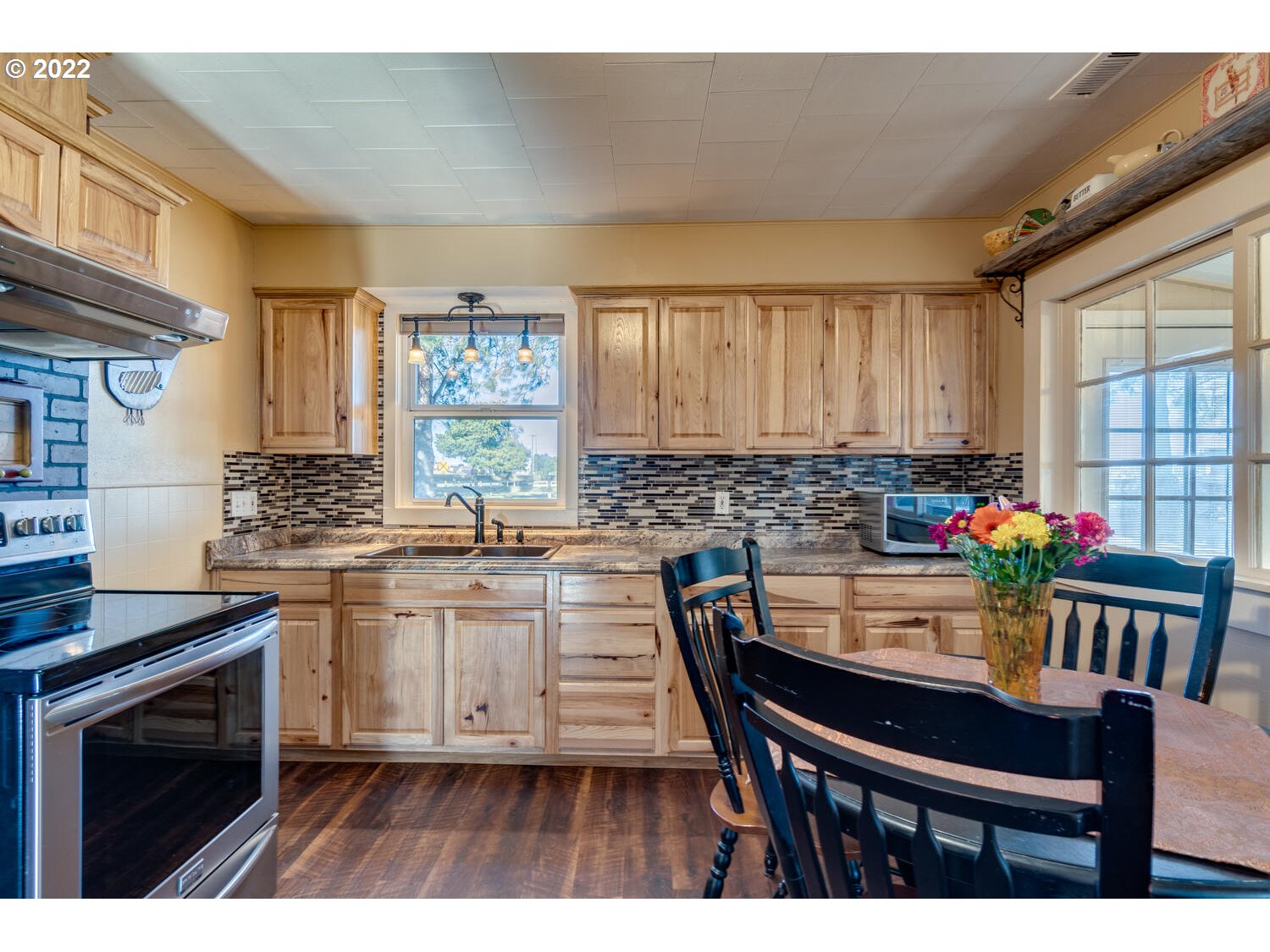 18876 Butteville Road Northeast Aurora, OR 97002 - Photo 29 of 32 a kitchen with granite countertop a stove a sink dishwasher a dining table and chairs with wooden floor