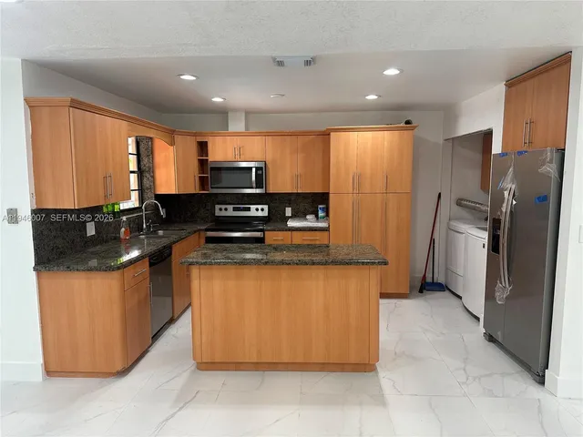 a kitchen with stainless steel appliances granite countertop a refrigerator and a stove