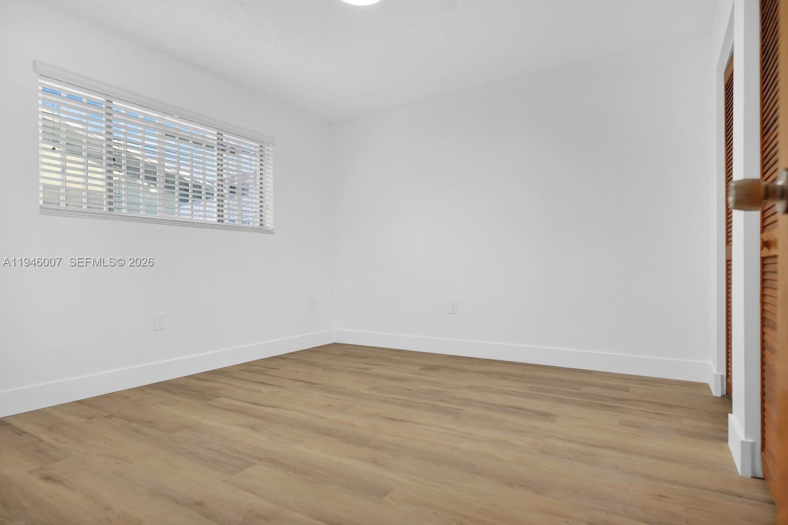 326 East 34th Street Hialeah, FL 33013 - Photo 14 of 26 an empty room with wooden floor and windows