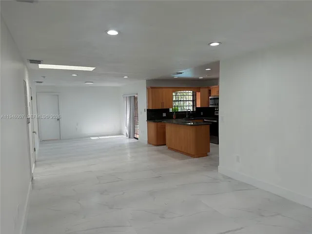 a view of a kitchen with a sink and an empty room