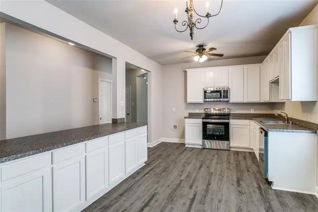 a kitchen with stainless steel appliances a stove a sink and white cabinets
