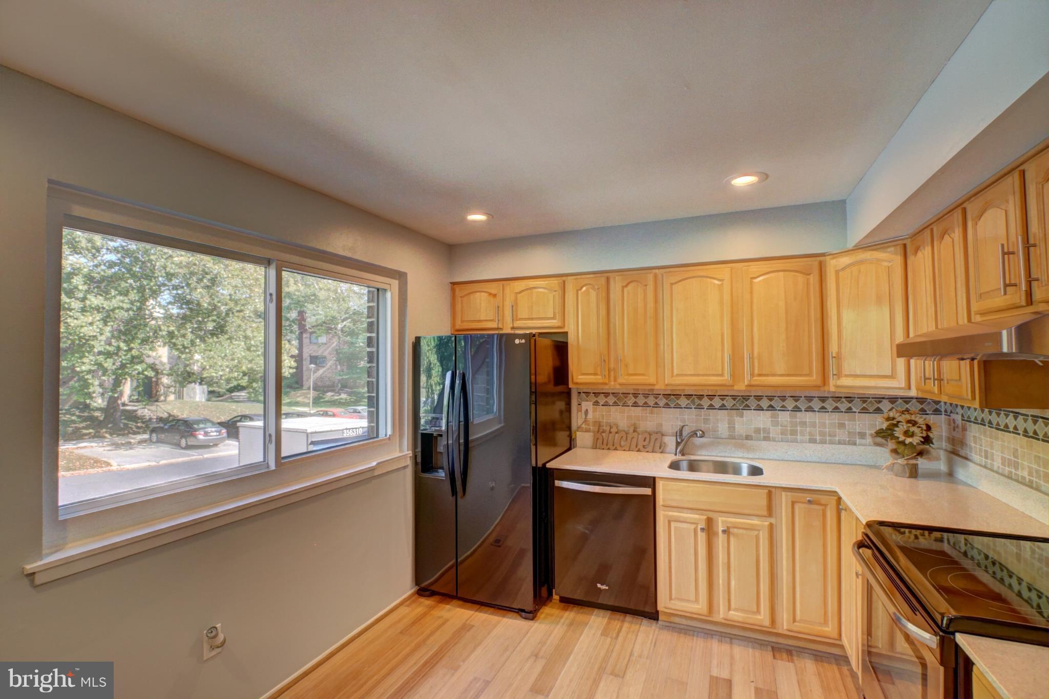 7068 Winter Rose Path Columbia, MD 21045 - Photo 2 of 30 a kitchen with stainless steel appliances granite countertop a refrigerator a sink dishwasher a stove and white countertops with wooden floor