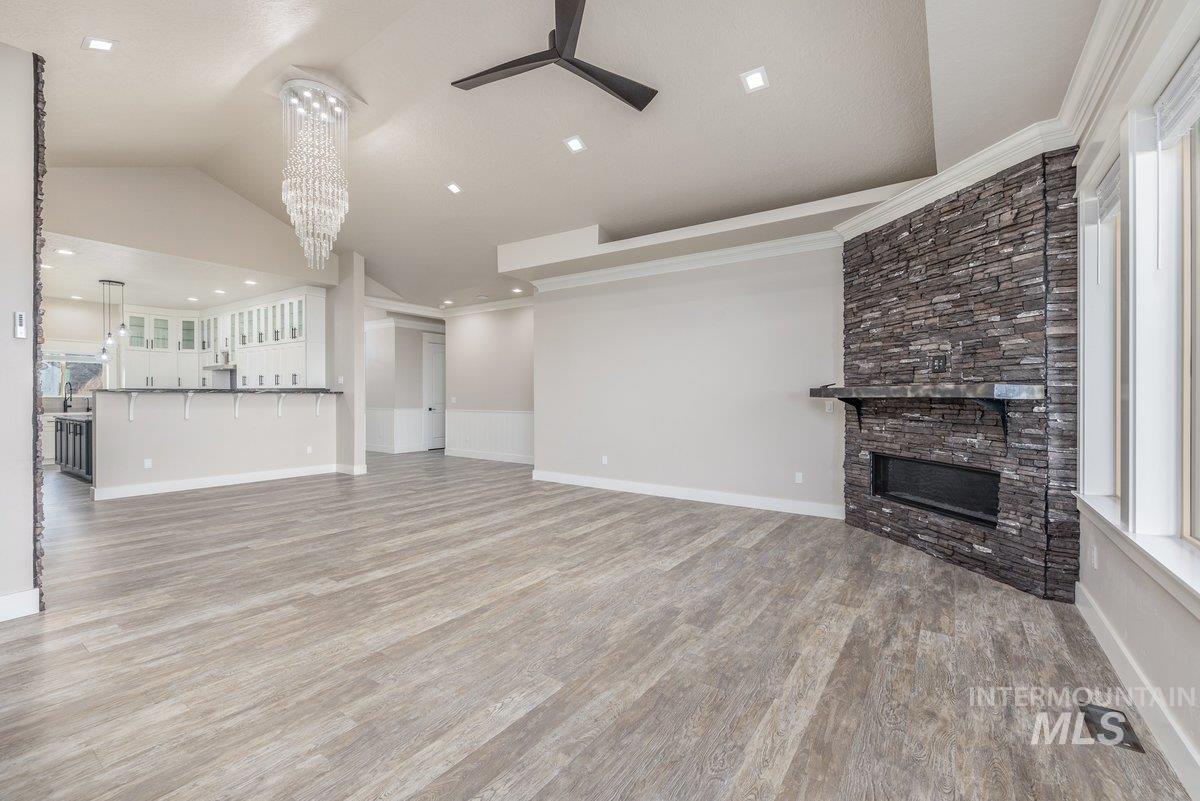 5990 West View Drive Meridian, ID 83642 - Photo 11 of 50 Unfurnished living room featuring a stone fireplace, light wood finished floors, a chandelier, lofted ceiling, and a ceiling fan