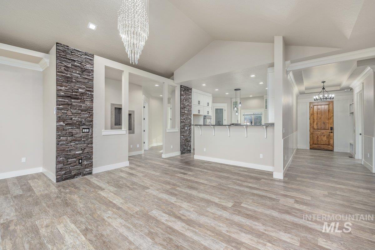 5990 West View Drive Meridian, ID 83642 - Photo 12 of 50 Unfurnished living room featuring a chandelier, light wood-style flooring, vaulted ceiling, and crown molding