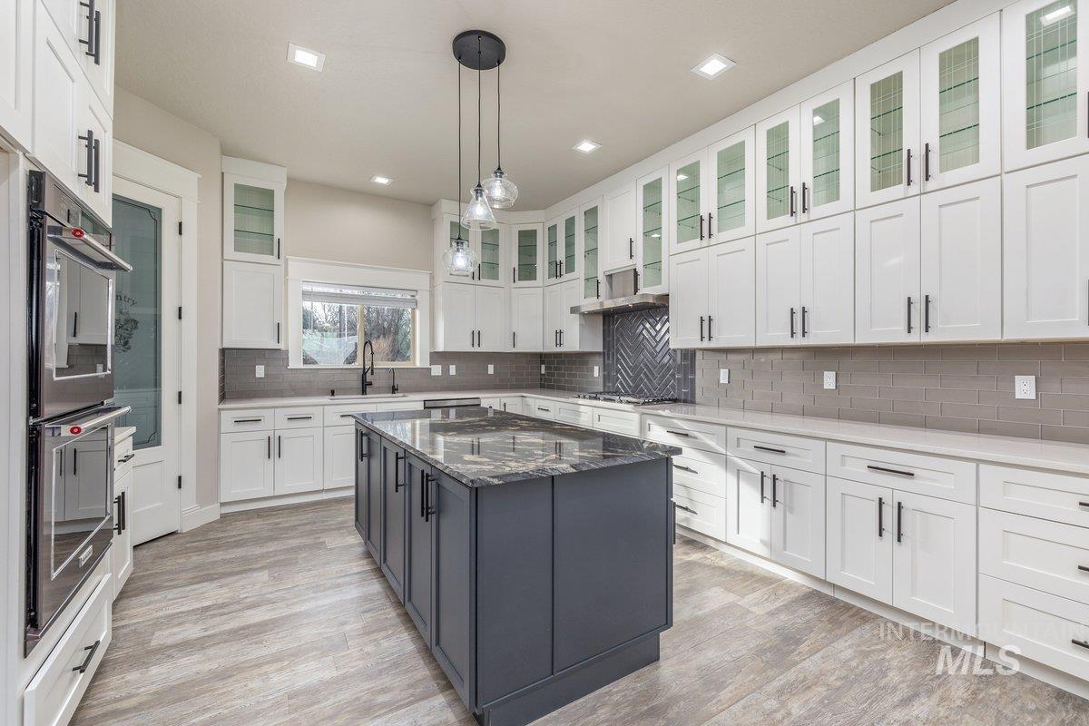 5990 West View Drive Meridian, ID 83642 - Photo 13 of 50 Kitchen with dark stone countertops, pendant lighting, white cabinetry, appliances with stainless steel finishes, and a center island