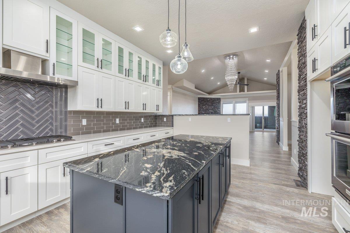 5990 West View Drive Meridian, ID 83642 - Photo 15 of 50 Kitchen featuring dark stone countertops, a kitchen island, lofted ceiling, white cabinets, and pendant lighting