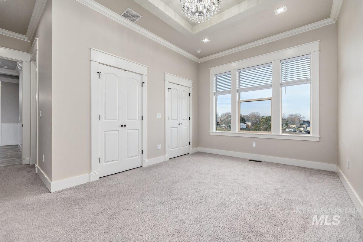 5990 West View Drive Meridian, ID 83642 - Photo 22 of 50 Unfurnished bedroom with two closets, ornamental molding, light carpet, and a chandelier