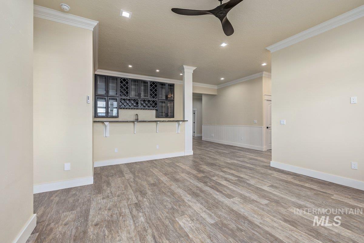 5990 West View Drive Meridian, ID 83642 - Photo 27 of 50 Unfurnished living room featuring wood finished floors, crown molding, ceiling fan, recessed lighting, and a wainscoted wall