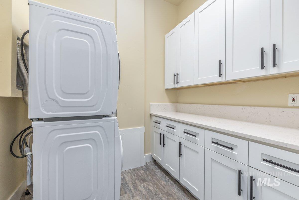 5990 West View Drive Meridian, ID 83642 - Photo 35 of 50 Laundry area with estacked washer and dryer, dark wood-type flooring, and cabinet space
