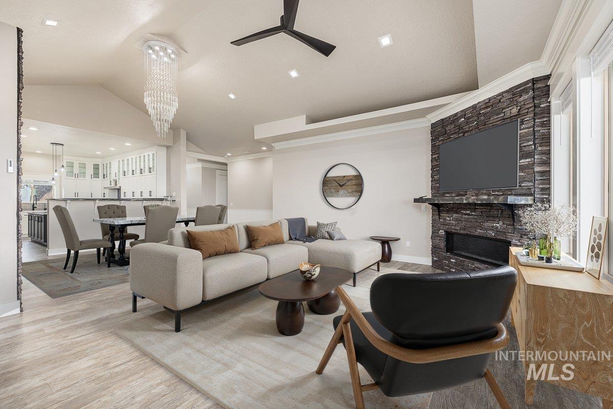 5990 West View Drive Meridian, ID 83642 - Photo 6 of 50 Living area with a large fireplace, vaulted ceiling, light wood-type flooring, a ceiling fan, and a chandelier