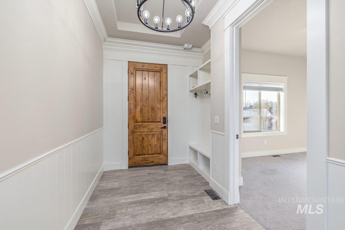 5990 West View Drive Meridian, ID 83642 - Photo 8 of 50 Entrance foyer with a chandelier, light wood finished floors, ornamental molding, and a raised ceiling