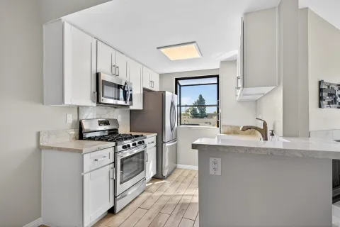 a kitchen with stainless steel appliances granite countertop a sink stove refrigerator and cabinets