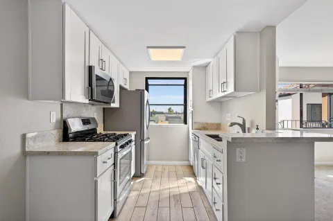 a kitchen with stainless steel appliances granite countertop a stove a sink dishwasher and a microwave oven with cabinets