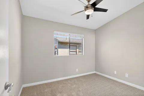 an empty room with a window and a fan
