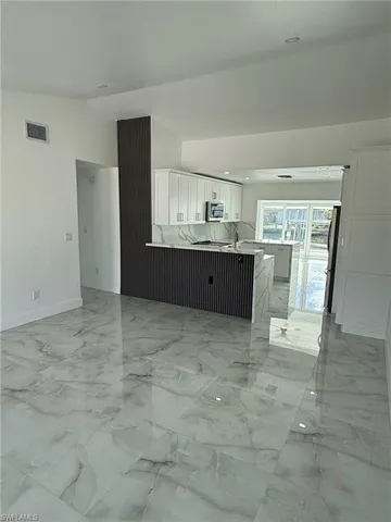 a view of kitchen with kitchen island granite countertop a refrigerator and a sink