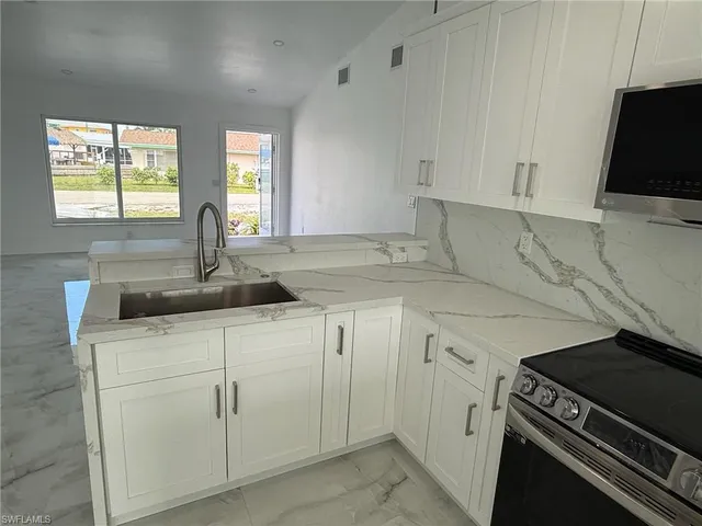a kitchen with white cabinets appliances and a sink