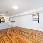 a view of kitchen and empty room with wooden floor