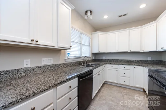 a kitchen with granite countertop white cabinets and a sink