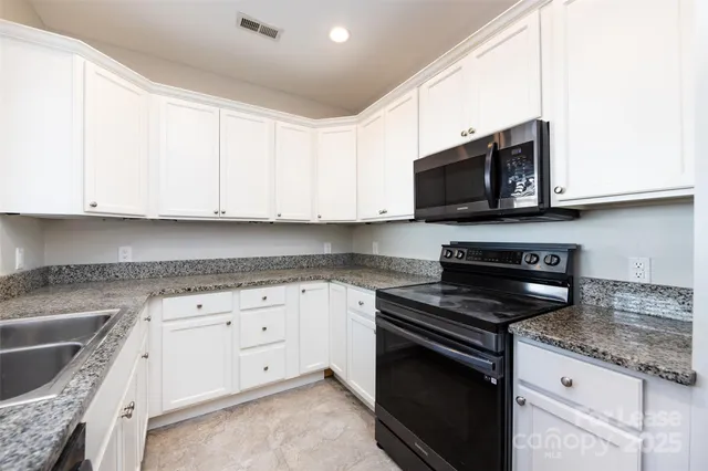 a kitchen with granite countertop white cabinets sink and stainless steel appliances