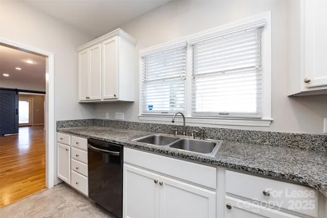 a kitchen with granite countertop a sink white cabinets and window