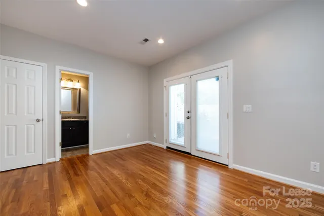 a view of an empty room with wooden floor and closet