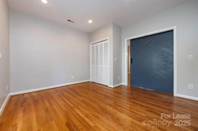 a view of an empty room with wooden floor and closet