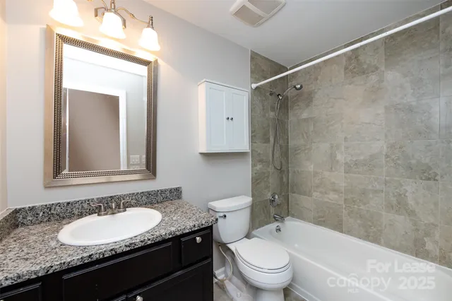 a bathroom with a granite countertop sink toilet a mirror and shower