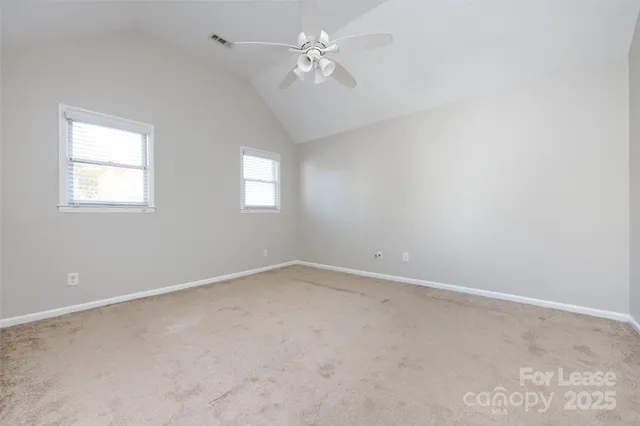 en empty room with windows and ceiling fan