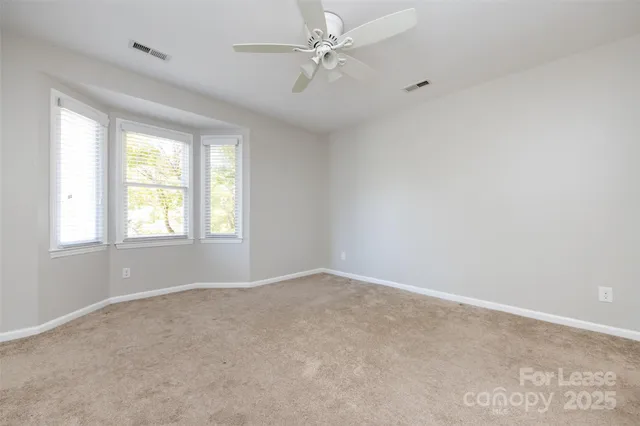 an empty room with windows and ceiling fan