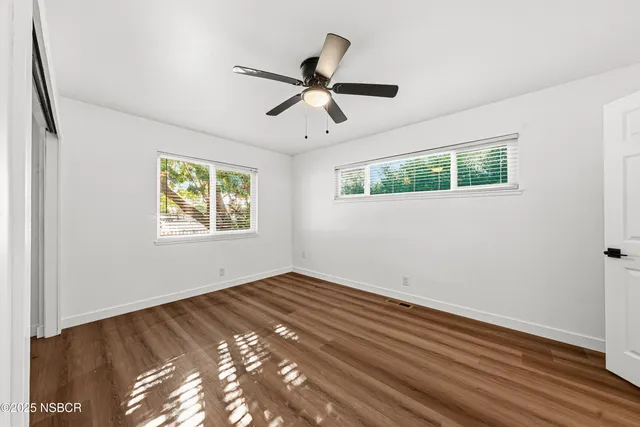 a view of empty room with wooden floor and fan