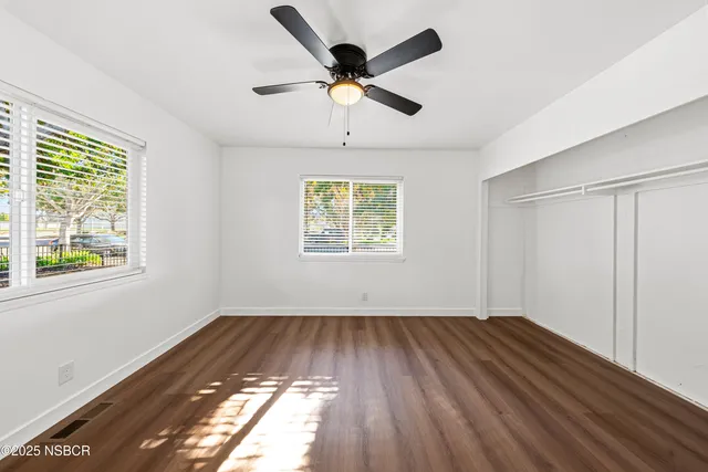 a view of empty room with wooden floor and fan